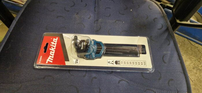 Förpackning med en Makita borrmall för styrning av borrdjup, placerad på en blå stol.