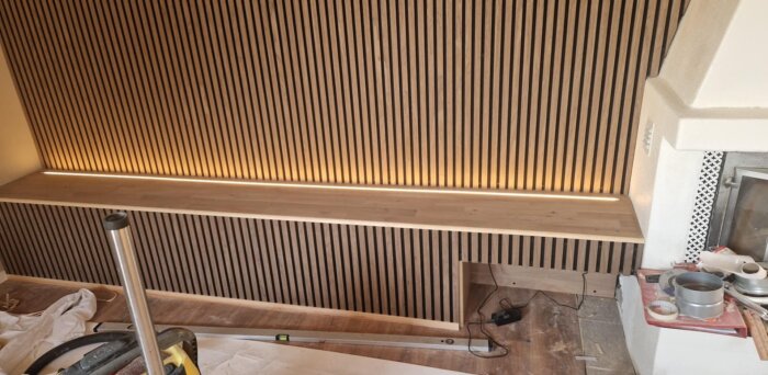 Träpanelvägg med inbyggd LED-list i TV-bänk, del av renoveringsprojekt.