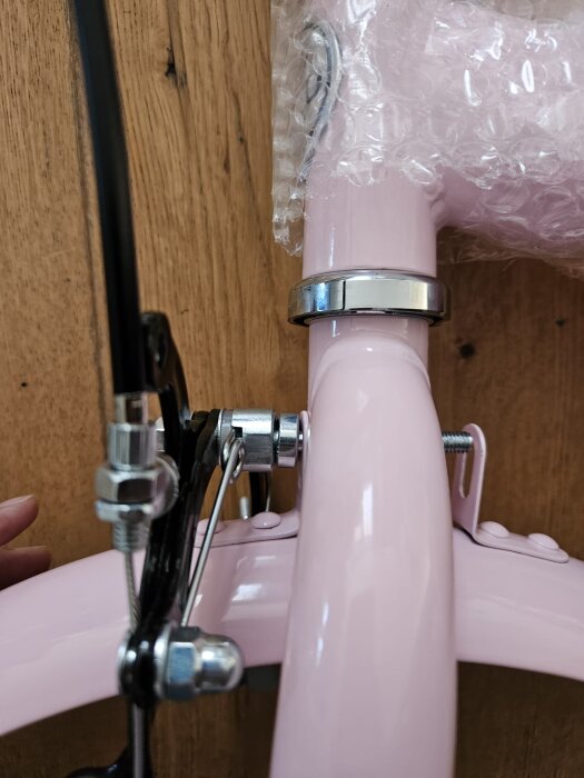 Närbild av rosa barncykel med monterad stänkskärm som inte når skruven.