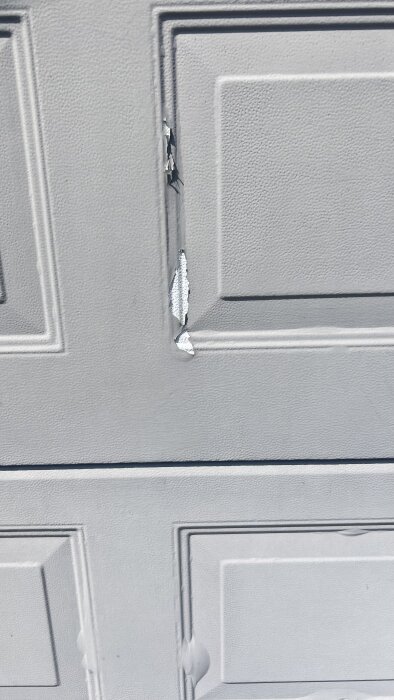 Flagnande och bubblande färg på äldre garageport, visar slitage och behov av renovering.