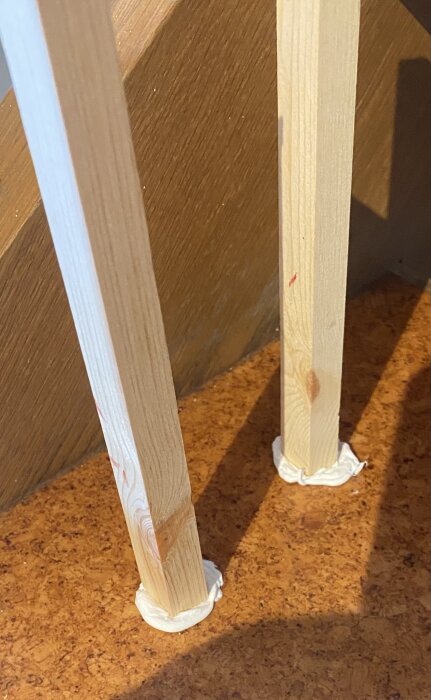 Två trästavar limmade på en brun yta, omgivna av vit limmassa, del av ett test av olika lim, inklusive Superfix+ och PL400.