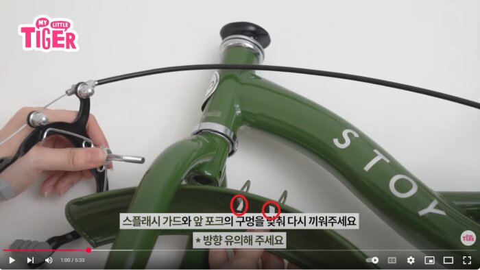 Grönt cykelstyre och gaffel med pågående montering av broms och skärm, text på koreanska visas.