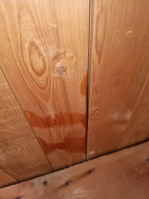 Fuktfläckar på träpanel i taket, indikerar läckage efter plåtdetaljinstallation.