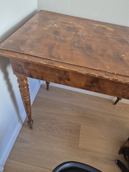 Gammalt träbord med repor och skador på ytan, utsmyckade ben och avskavda kanter.