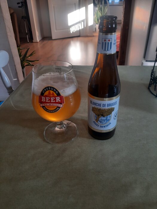 Belgisk veteöl i glas och flaska på bord, etikett "Blanche de Bruges".