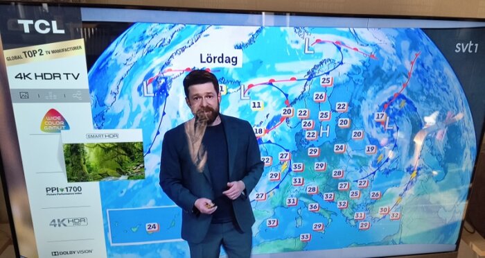 Väderrapport på en TCL-TV med grafik och väderpresentatör, skärmens vänstra sida visar TV-funktioner och kvalitetsmärken.