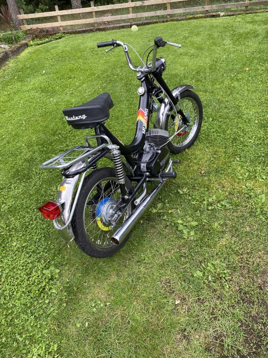 Svart Mustang-moped av årgång 1984 med tre växlar, parkerad på en gräsmatta.