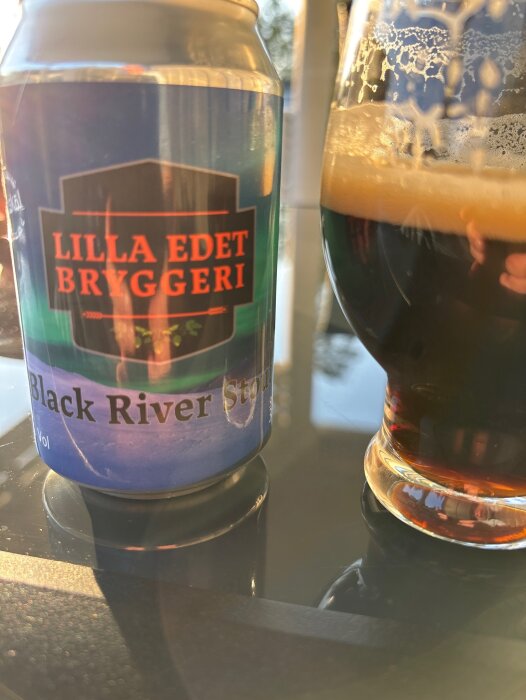 Burk med "Lilla Edet Bryggeri" och glas med mörk öl.