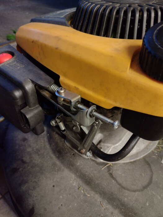 Moddad gräsklippare med gul kåpa och egenbyggd gasvajerslösning av användaren, med ny bränsleslang och luftfilter installerat.