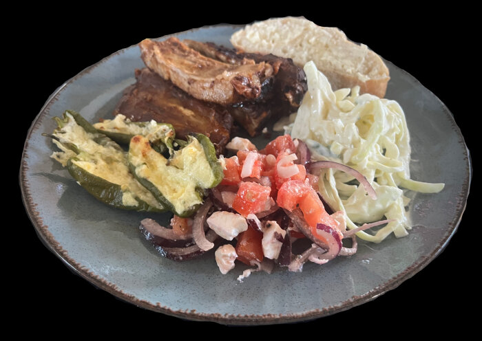 Tallrik med kamben, coleslaw, ugnsstekta fyllda padrones, nybakat bröd och tomat- och fetaostsallad.