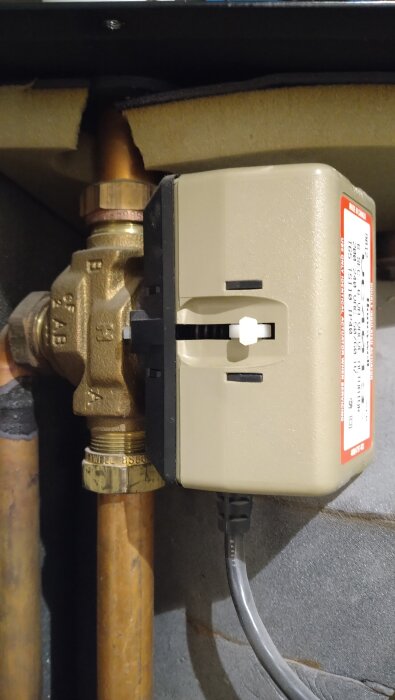 Ventil med etiketten "Just 4013" och en spak på sidan, monterad på kopparrör.