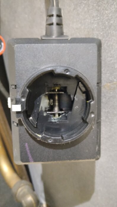 En närbild av en svart anslutning eller uttag med synlig inre komponent och kabel upptill. Inget synligt slitage eller sprickor.