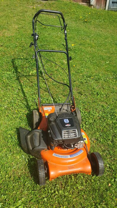 Orange gräsklippare Husqvarna Royal 52SE på gräsmatta, sedd från ovan, med svarta handtag och etiketter.