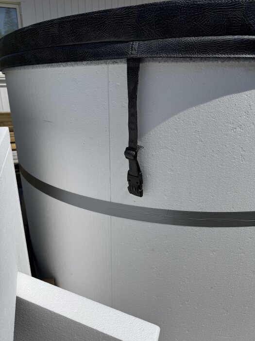 Terasspool omsluten av isolerande frigolit, en rem och spänne på locket synligt.