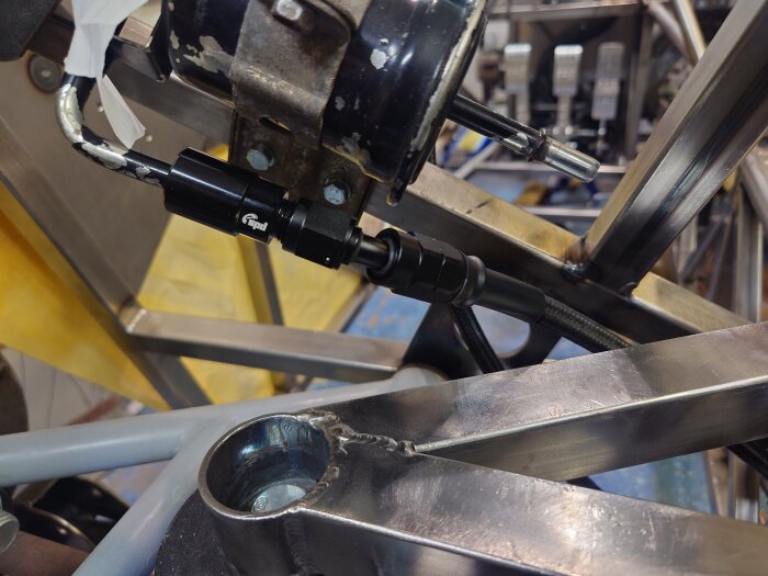 Bild på en monterad bränsleslang med en AN-koppling fäst vid en metallram, en del av ett pågående renoveringsprojekt.