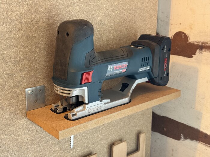 Jigsaw tool on a simple wall-mounted shelf, showcasing organized storage solution in a workshop setting.