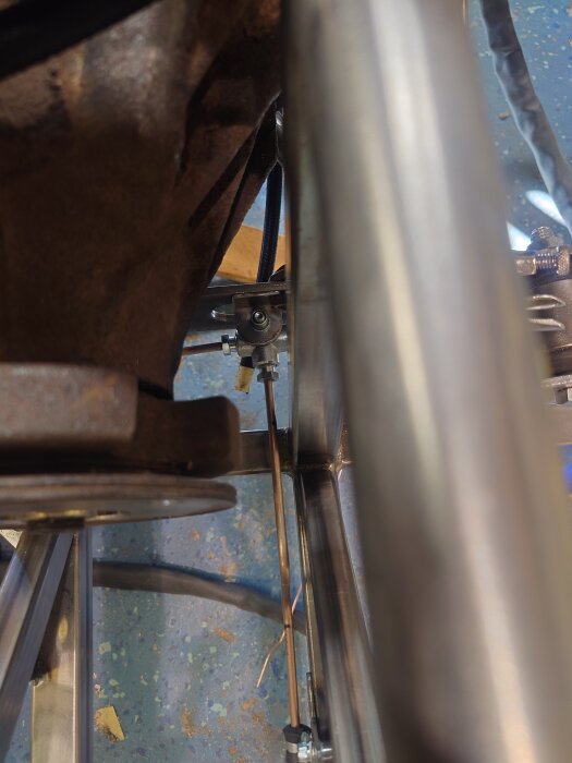 Metallkonstruktion med runda och platta stålrör samt delar som skruvar och muttrar monterade på en golvyta.