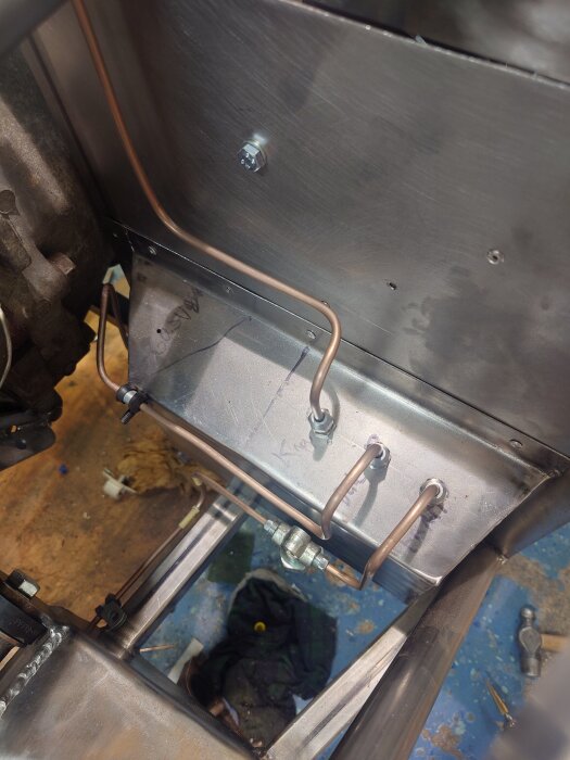 Rördragning i metallkonstruktion med kopparrör och beslag, del av renoveringsprojekt i verkstadsmiljö.