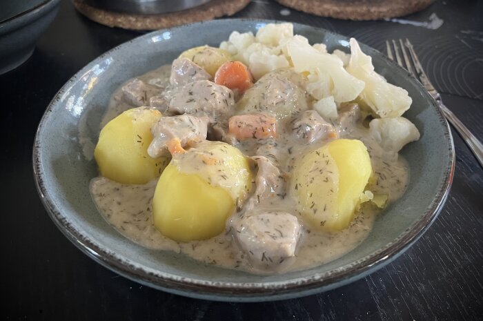 Tallrik med dillkött och dillsås serverat med kokt potatis och blomkål.
