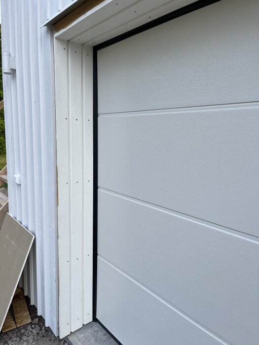 Ny monterad garageport med vit panel och foder.