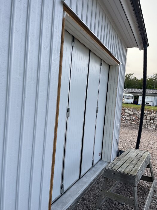 Monterade portar på en byggnad, inkapslade med panel, med en stege framför.