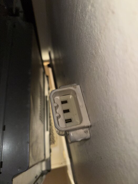 Gammalt trestifts eluttag för spis på väggen, delvis dolt i skugga, installerat i ett kök.