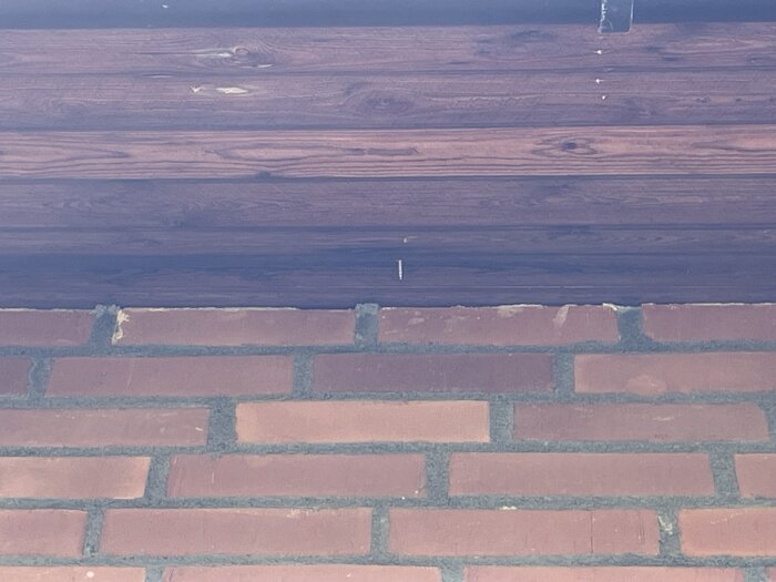 Tegelvägg med skråande tak; synlig skruv sticker ut under takets framkant.