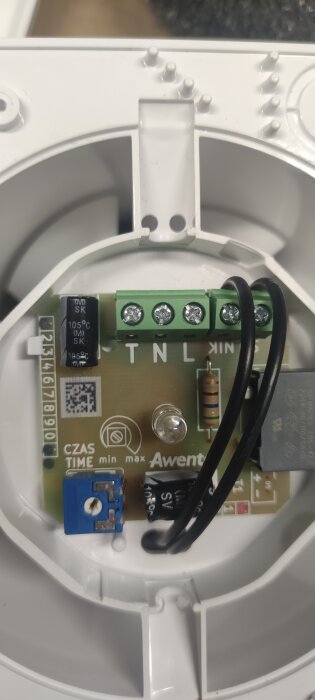 Närbild av kopplingsplint och komponenter på ett kretskort till en badrumsfläkt, inklusive anslutningar märkta T, N, L.