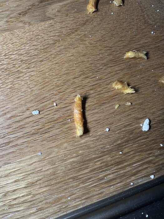 Oljigt sågspån på trägolv från en håltagning i väggregel för ethernet-kabeldragning, beskrivet som luktande kåda.