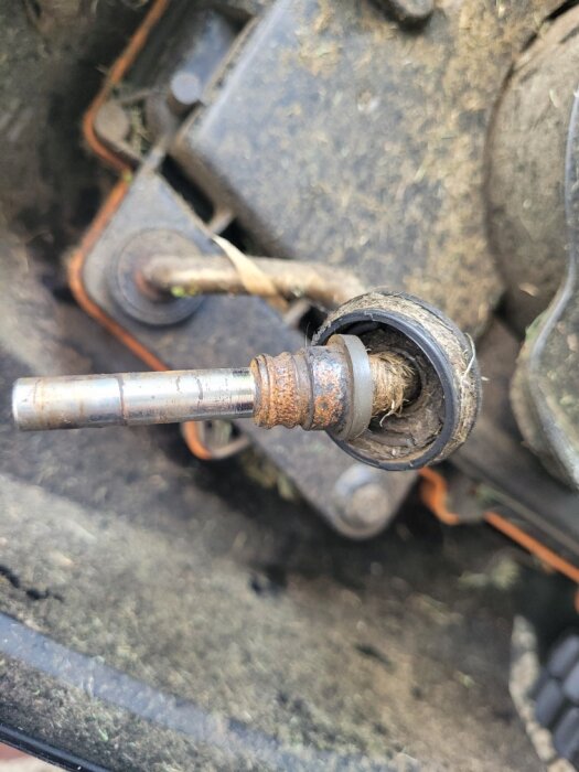 Slitet och rostigt hjulnav till Worx Landroid, med synlig rotoraxel och slitage i lagerhuset, omgiven av gräsrester.