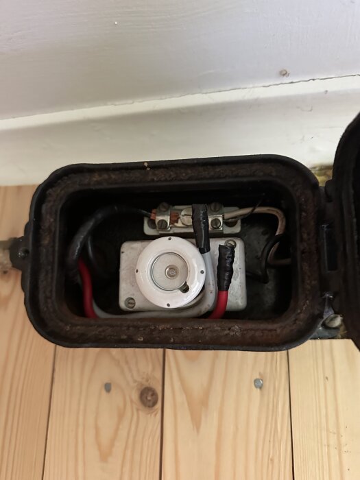 Öppnat elskåp med säkring på trägolv.