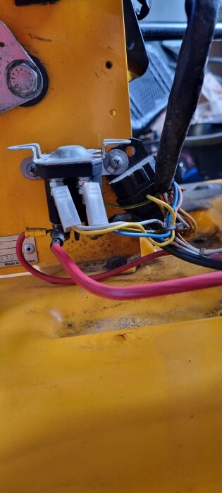 Elektriska kablar och anslutningar på en gul yta med röd och gul kabel, samt olika komponenter i ett byggprojekt.