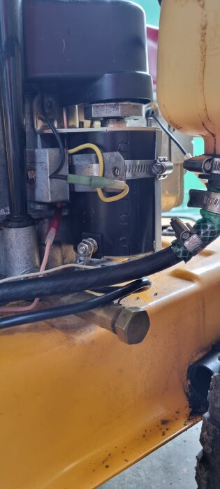 Gula och svarta kablar är anslutna till en elektrisk komponent på en maskin med gul bas.