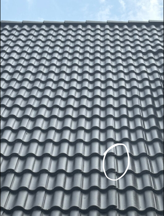 Tak med tegelpannor, en panna markerad där den ligger feljusterad i förhållande till de andra.