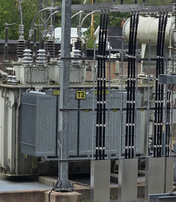 Transformatorstation med anslutningar och skenor på stödisolatorer. Kulbultar synliga på både upp- och nedsida. T2 skylt markerar utrustning.