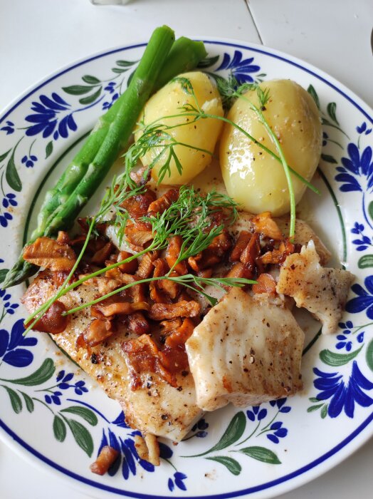 Tallrik med fisk, kantareller, potatis och sparris, garnerad med dill.