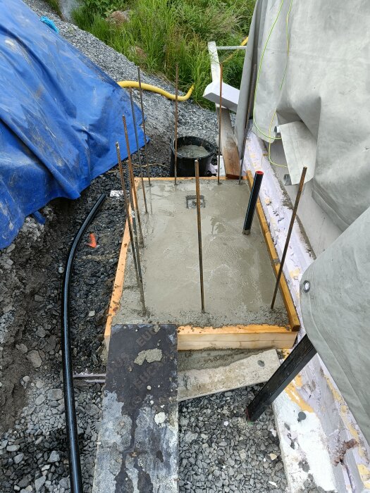 Nygjuten betongplatta för teknikrum, omgiven av armeringsjärn och byggmaterial.