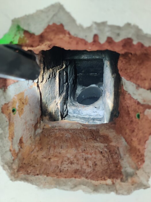 Närbild av en insida av skorsten där en ny sotlucka har installerats, med tegelväggar och mörk öppning.