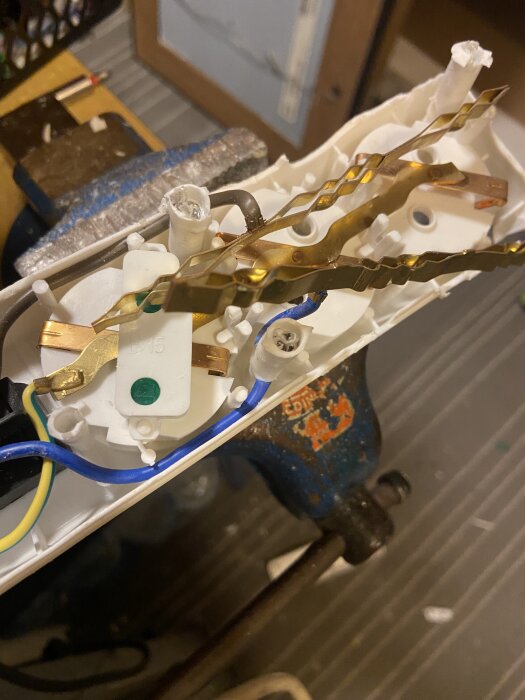 Inuti ett öppnat grenuttag med synliga ledningar och anslutningar, placerat i ett garage.