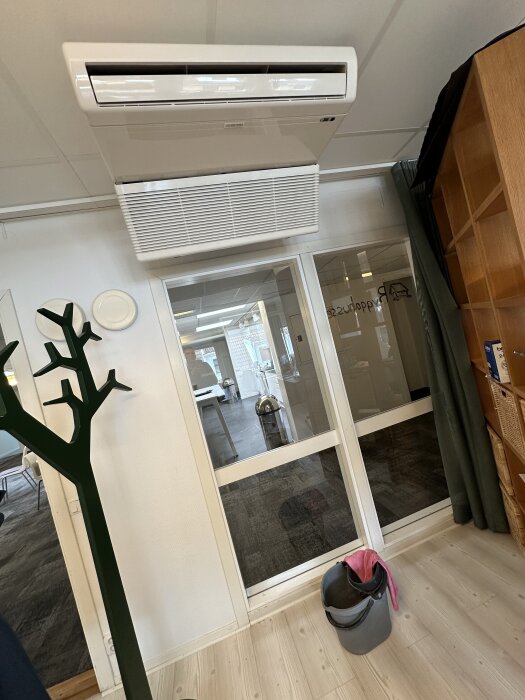 AC-enhet i taket på ett kontor med en hink och trasa på golvet nedanför för att hantera kondensvattenläckage.