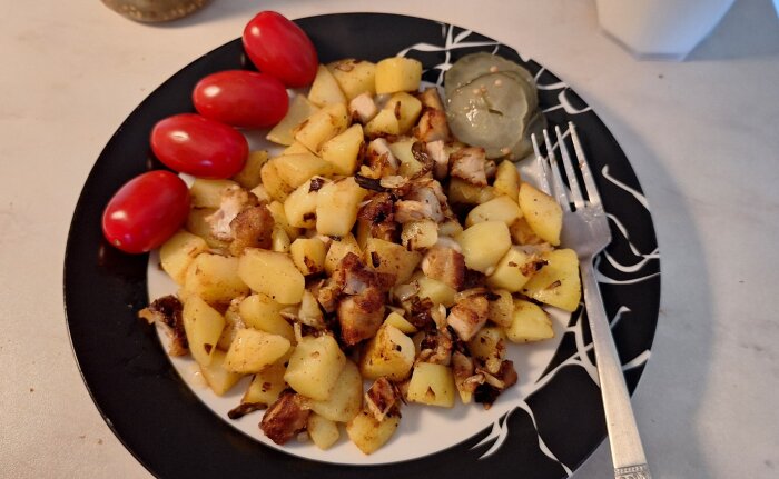 Tärnad potatis och kött på en tallrik, med körsbärstomater och inlagd gurka, klar att serveras.