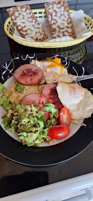 Tallrik med stekt falukorv, stekta ägg, potatisgratäng, sallad med vitkål, mungbönor, tomat och knäckebröd med smör i en korg.