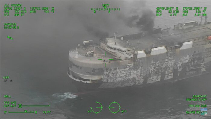 RO-RO-färja med omfattande brandskador och rök, fotograferad från luften.