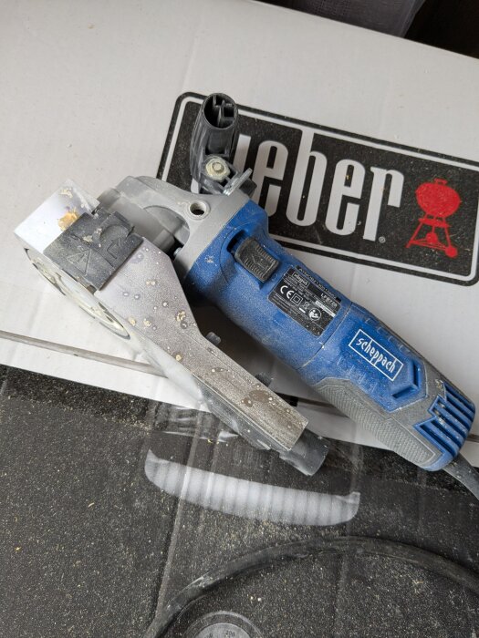 Scheppach lackfräs LFR720 placerad på en Weberlåda, visar slitage och damm efter testning på fasad.