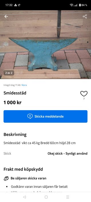 Blå smidesstäd stående på stenplattor och trä, med en bakgrund av ett trästaket. Används för smide och metallbearbetning.