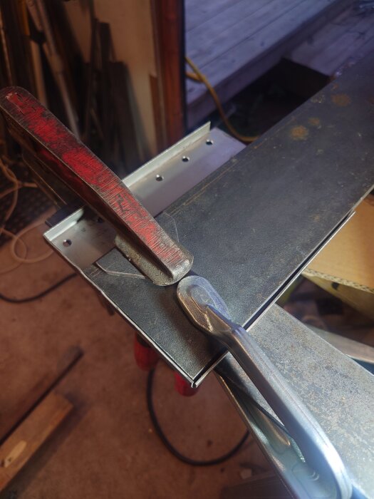 Metallklämmor håller en bit 1,5 mm rostfritt stål på plats under plåtslageriarbete i ett verkstadsutrymme.