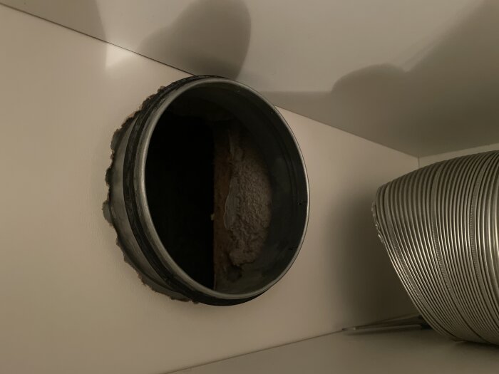 Flexrör och ventilationsstos i närbild, där flexröret inte riktigt når stosens kant, vilket visar ett problem med kopplingen.