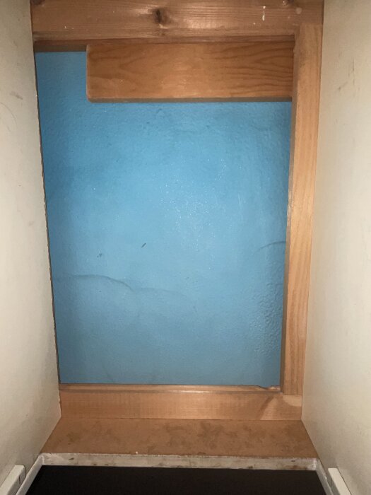 Utrymme under köksbänk markerat blått, redo för borttagning och ny diskmaskin, med synlig träram.