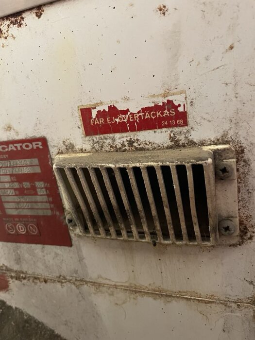 Gammal Wascator tvättmaskin från 1973 med ventil på baksidan, märkt "Får ej övertäckas", samt rost och smuts runt ventilområdet.