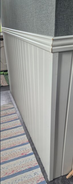 Vitt plankväggshörn med spont i hörnet och list upptill.